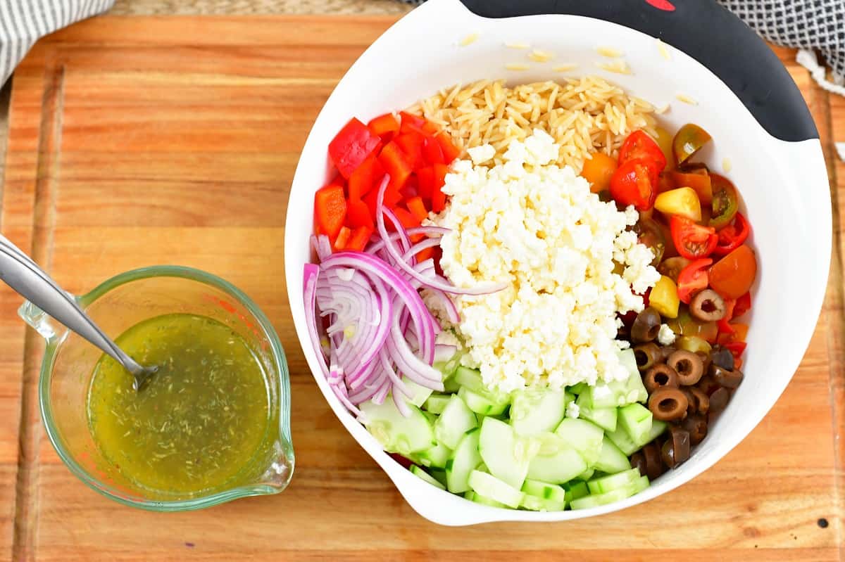 ingredients for the salad in a bowl and the dressing in cup