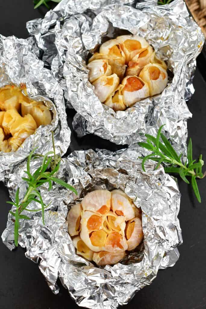 three cloves of roasted garlic each wrapped in foil
