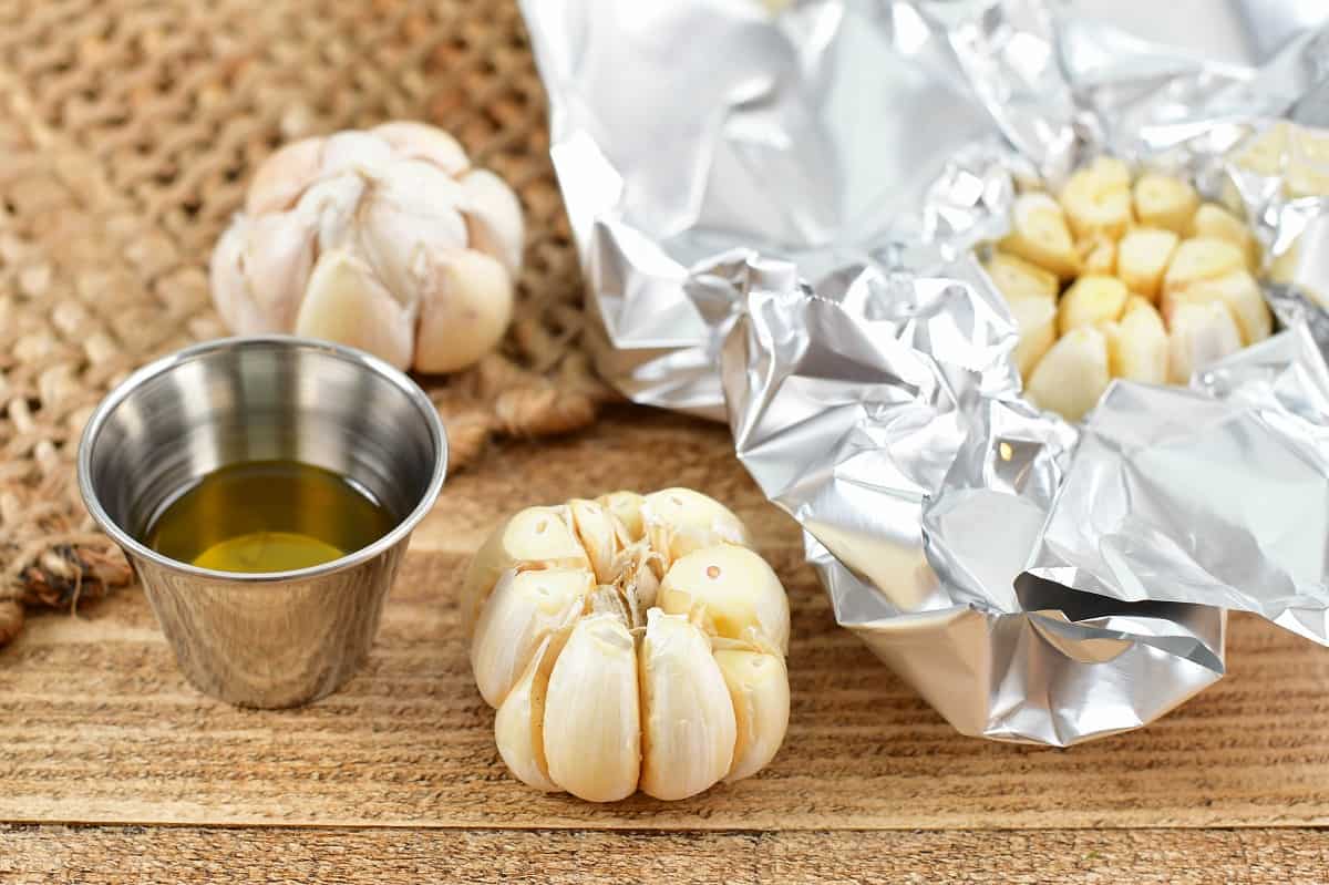 closeup of garlic bulb with tip cut off with another in foil