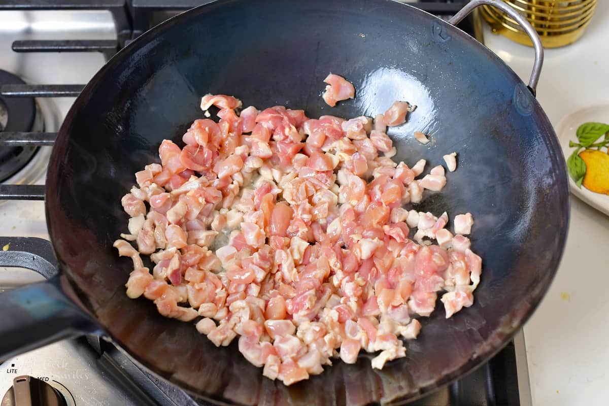 sautéing minced chicken in a wok