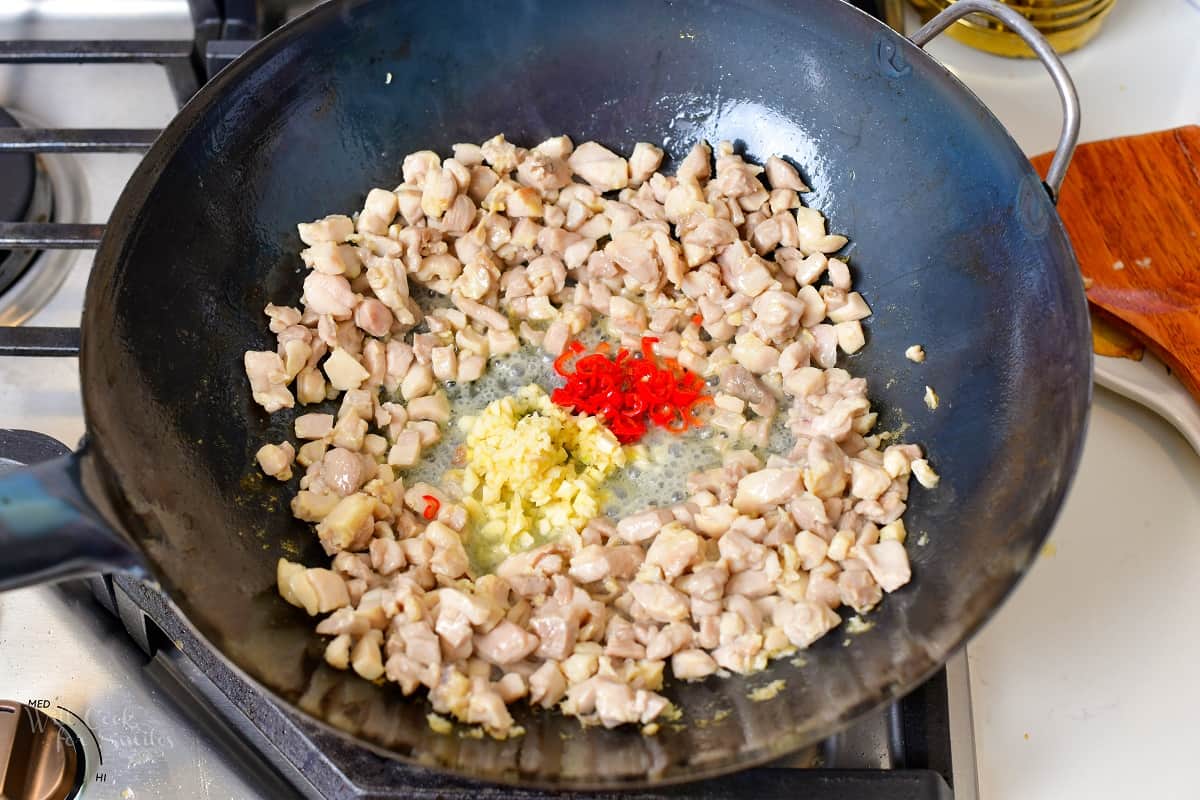 adding garlic and Thai chili peppers to the chicken