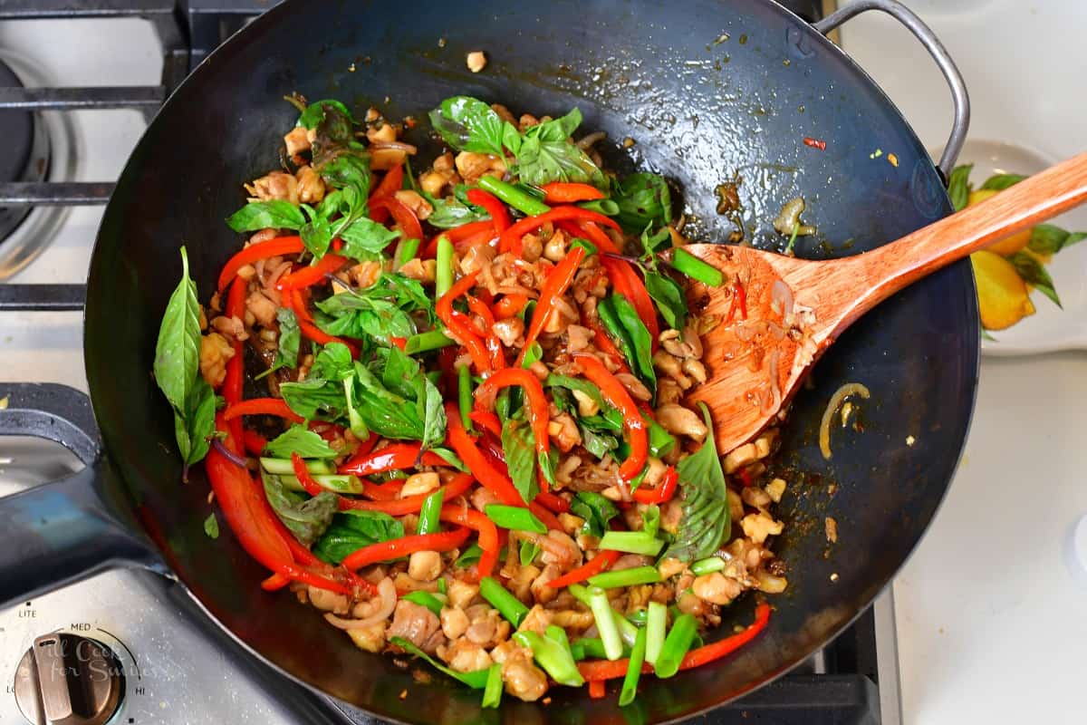 stirring in basil and scallions with chicken in a wok