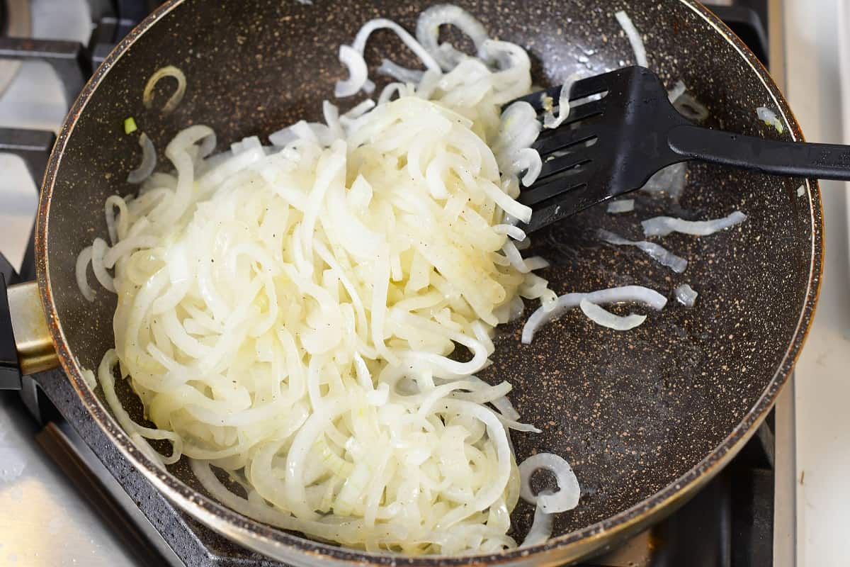 stirring onions in the pan as they start to cook