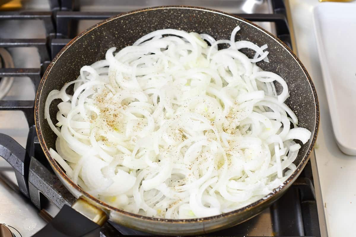 uncooked onions in a pan with salt and pepper