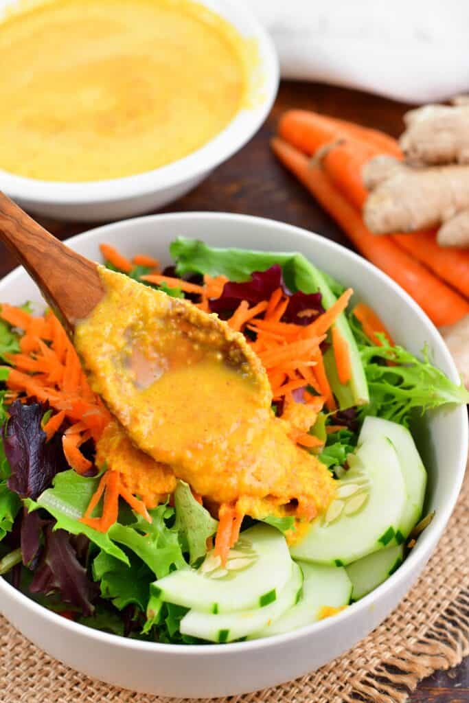 adding carrot ginger dressing to the salad