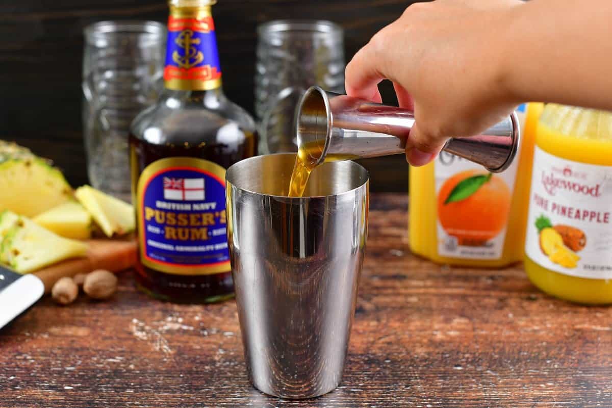 pouring in navy rum into the cocktail shaker