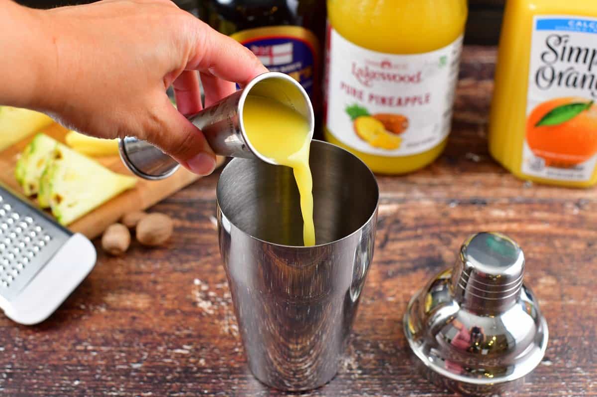 adding orange juice to cocktail shaker