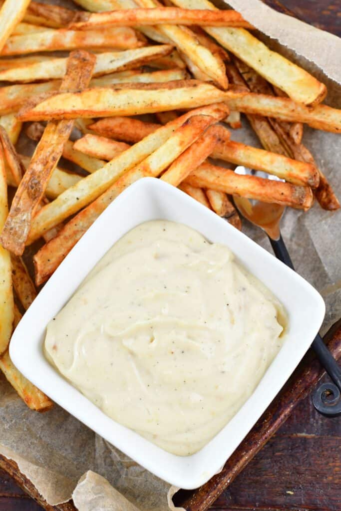 top view of aioli in a bowl surrounded by fries