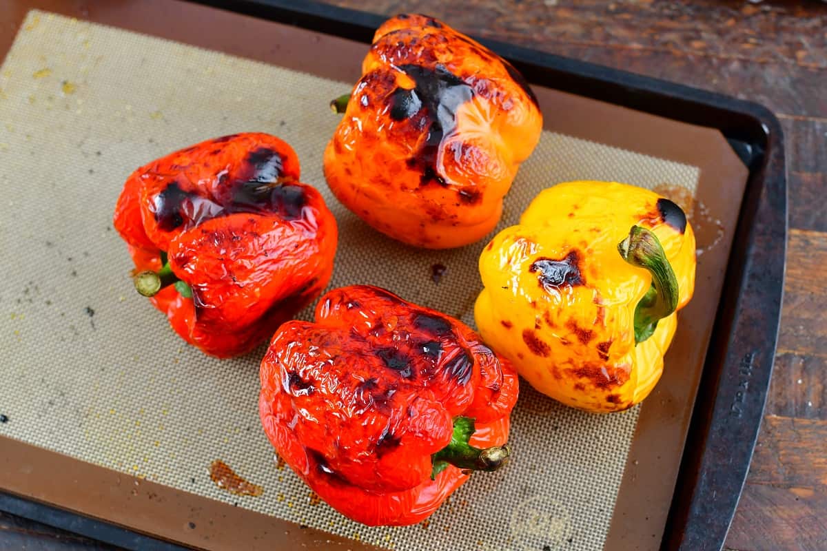 four bell peppers on the baking sheet after roasting