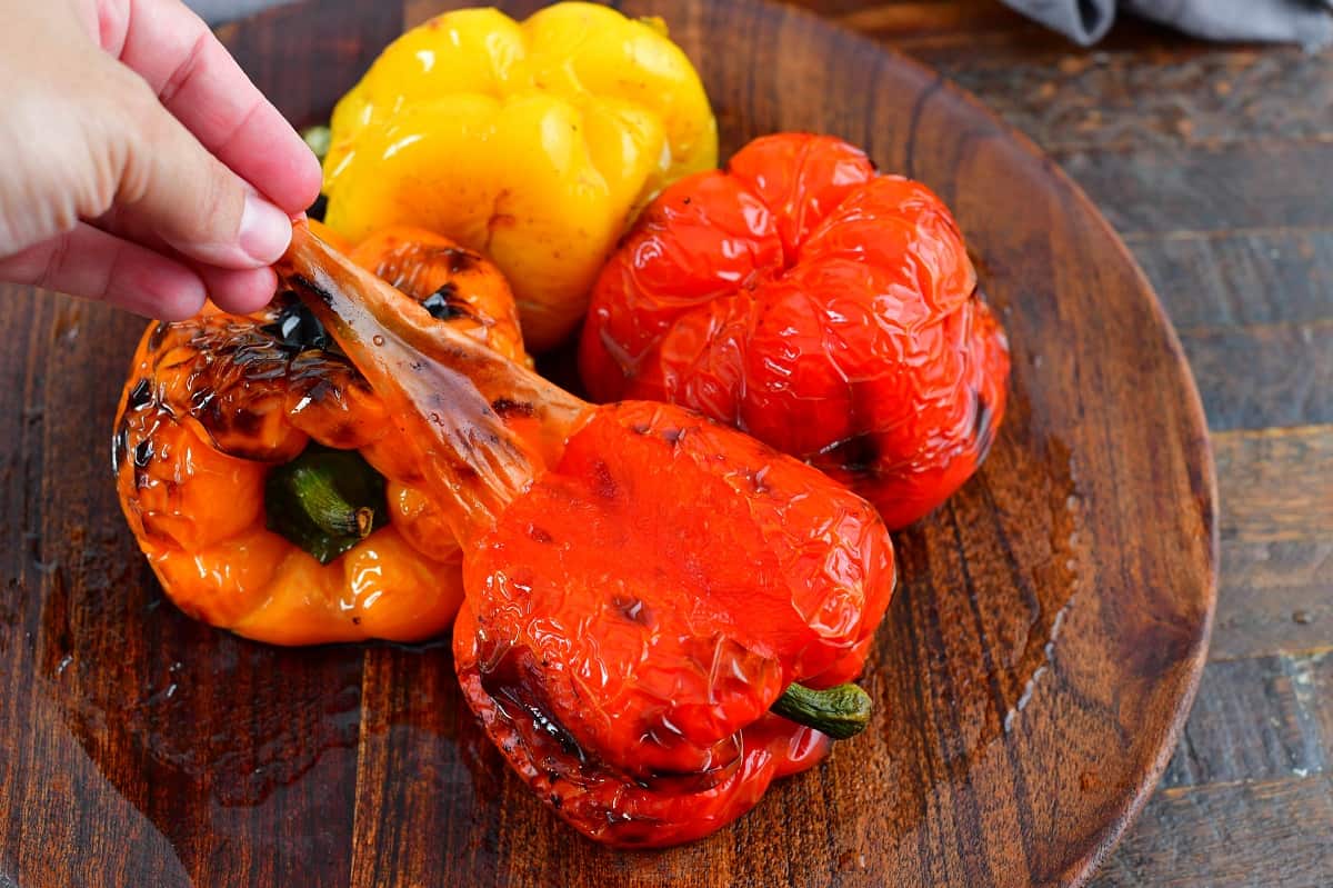 peeling off the skin from roasted red peppers