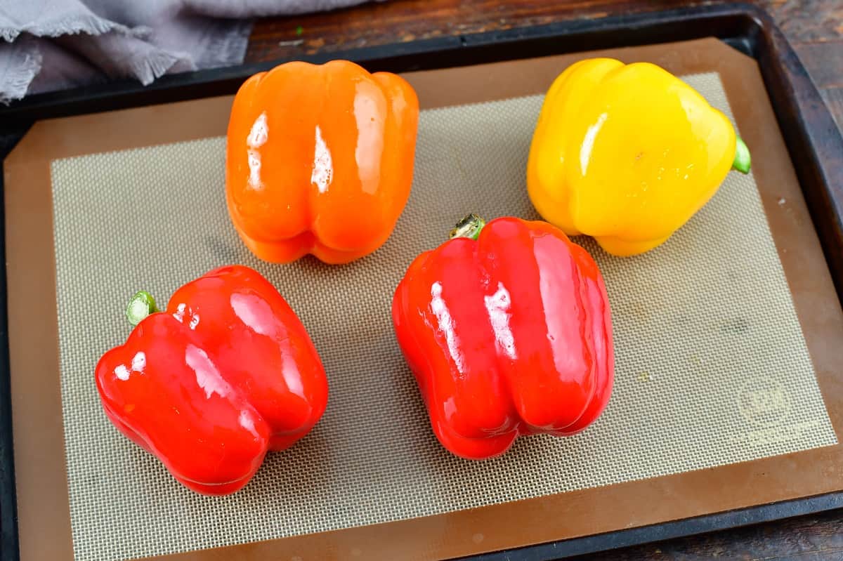 four bell peppers on a baking sheet robbed in oil