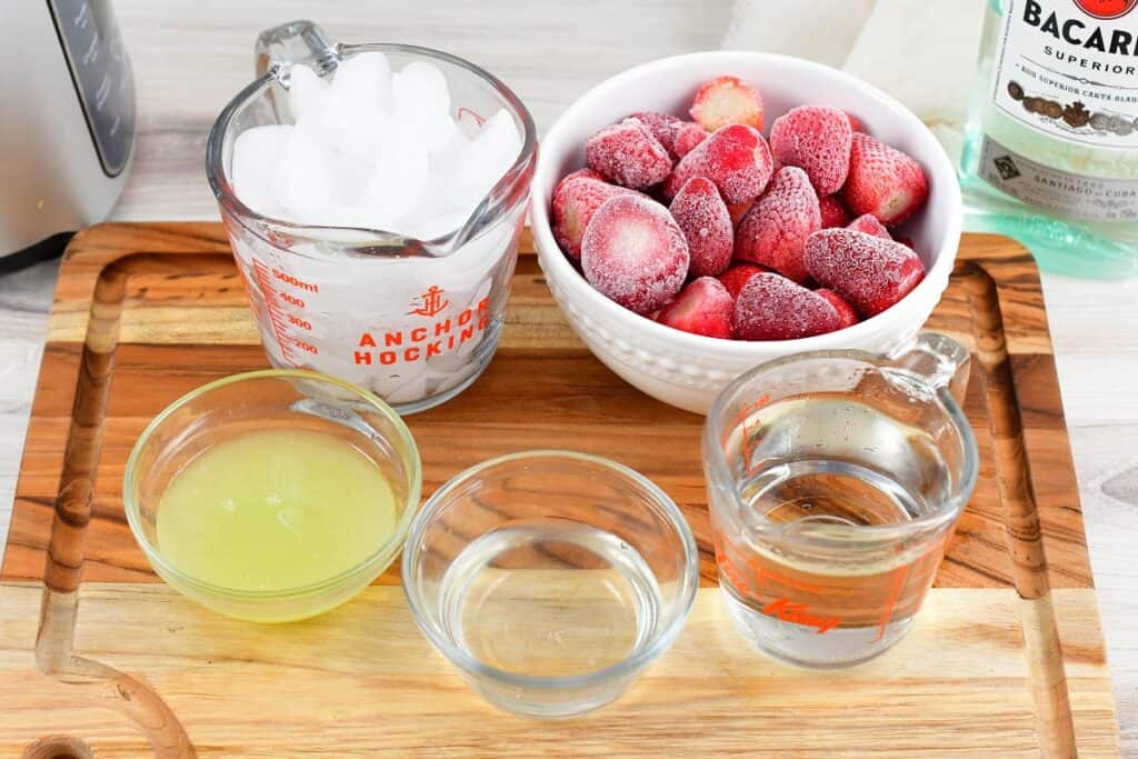 ingredients to make strawberry daiquiri on a cutting board