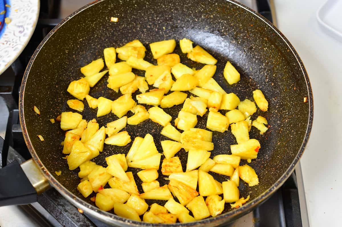 sautéing pineapple chunks in a pan