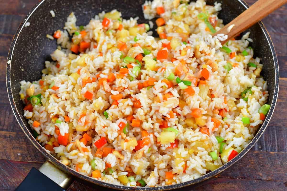 mixing pineapple fried rice with the sauce in the pan