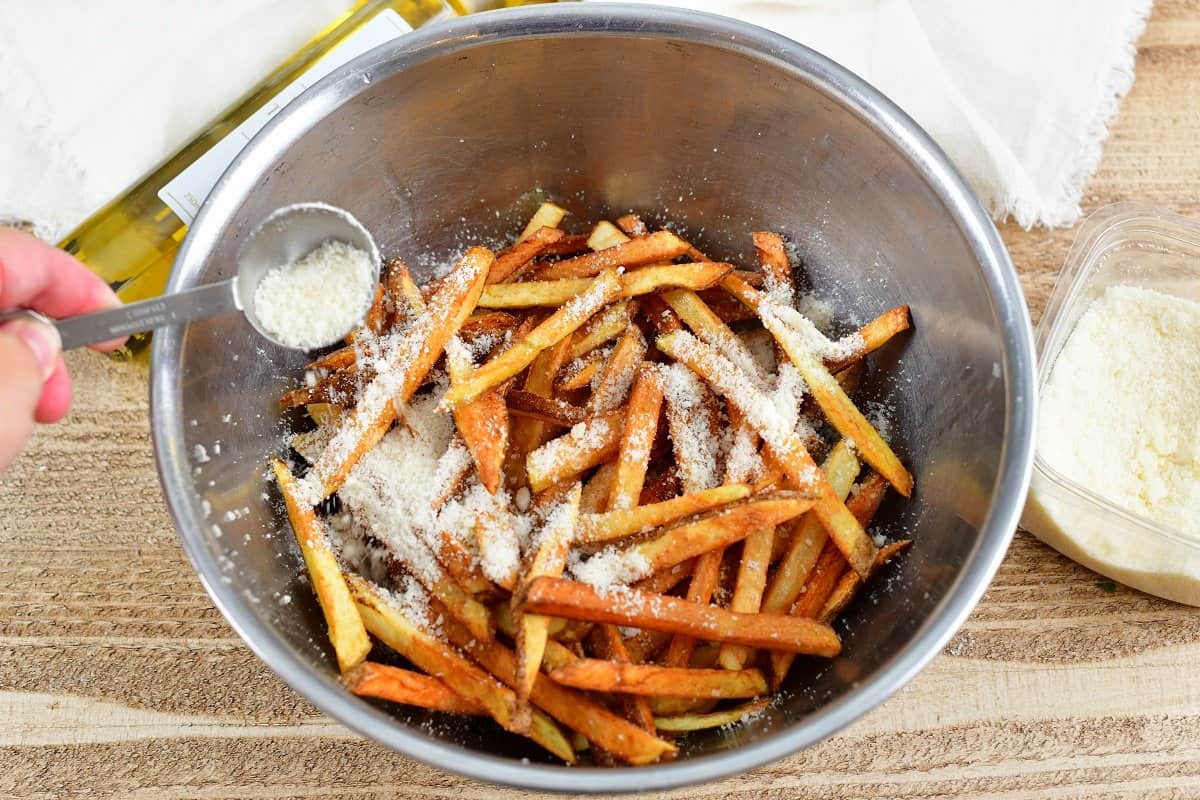 adding Parmesan cheese to cooked fried in a bowl