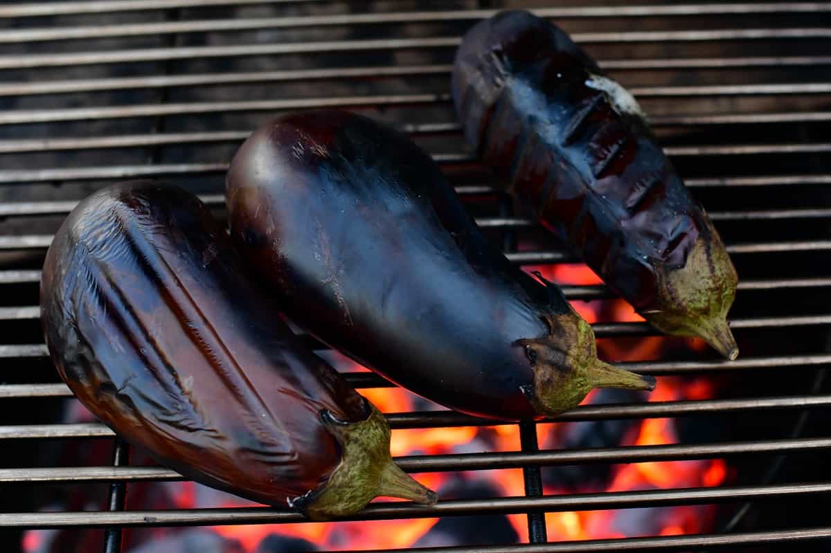 three eggplants on the grill cooking
