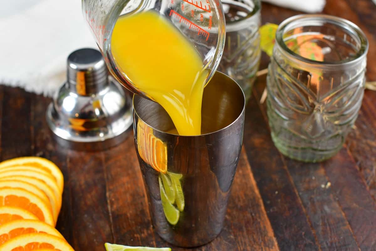 pouring in orange juice into the cocktail shaker