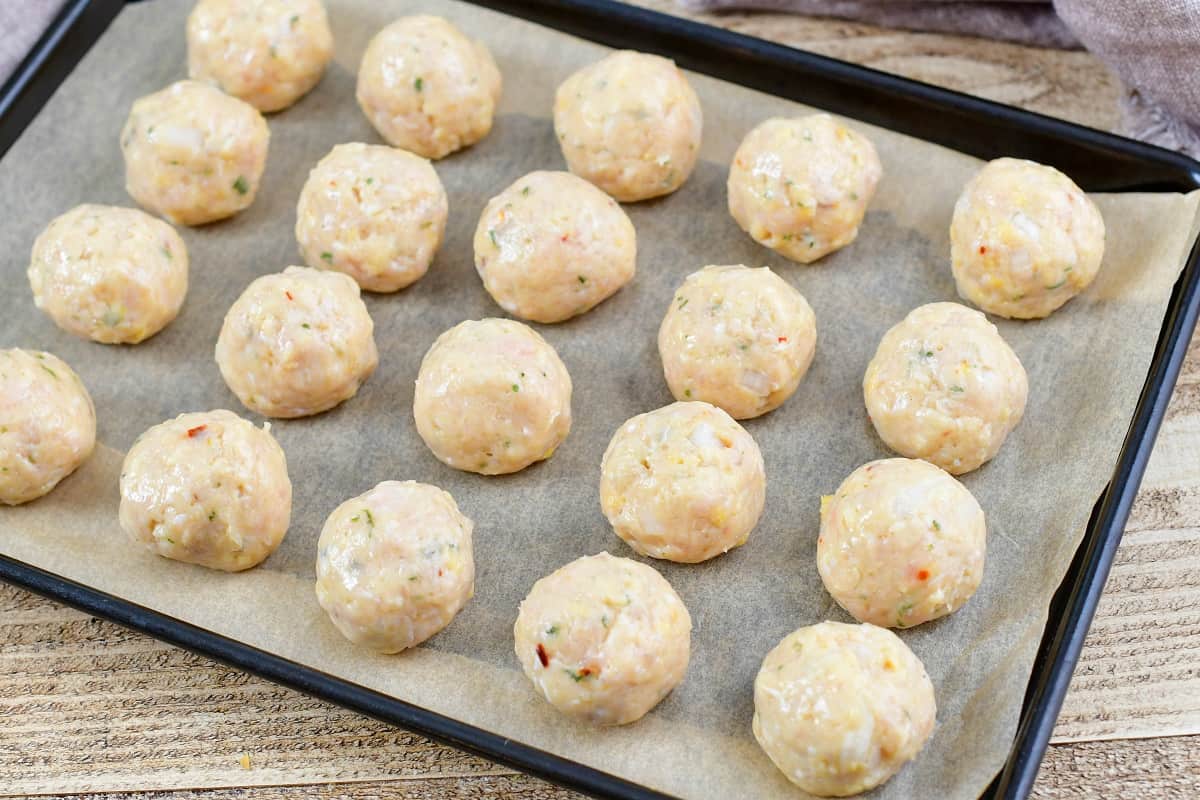 rolled chicken meatballs on a baking sheet