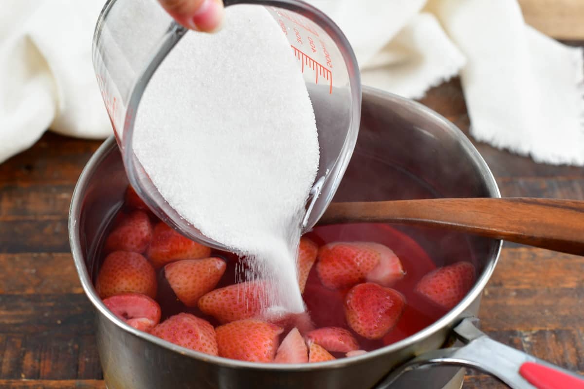 adding sugar to the hot strawberry water
