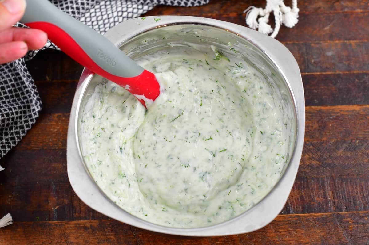 mixing the cucumber yogurt sauce in a mixing bowl