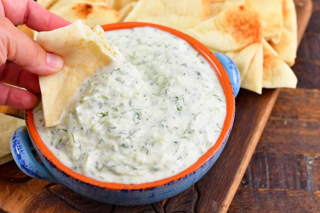 closeup of dipping into the tzatziki sauce with pita