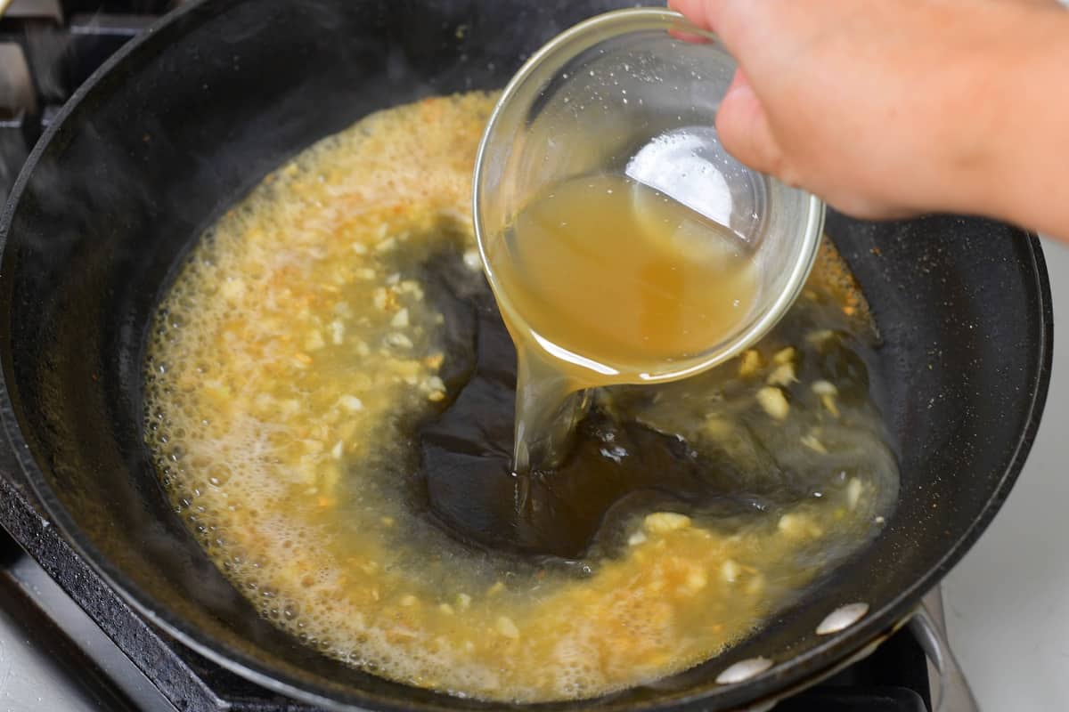 adding chicken stock to the pan