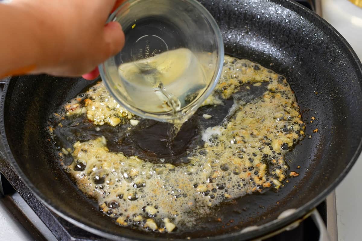adding whine to the pan with garlic
