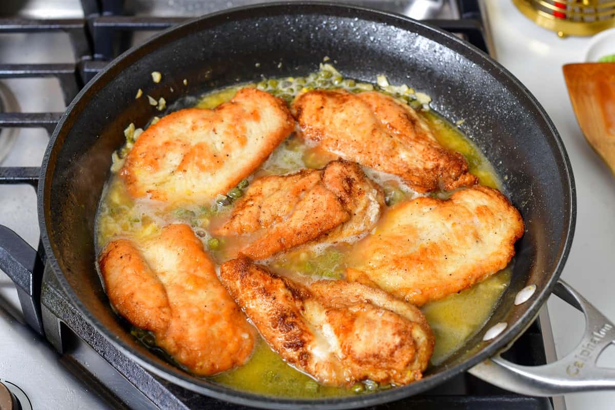 seared chicken cutlets cooking in sauce