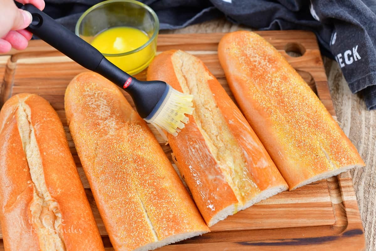 brushing tops of Cuban bread with butter