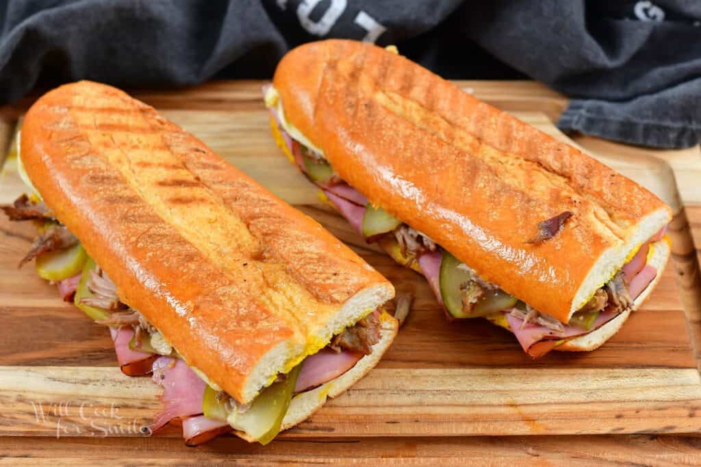 two long cooked Cuban sandwiches on the board.
