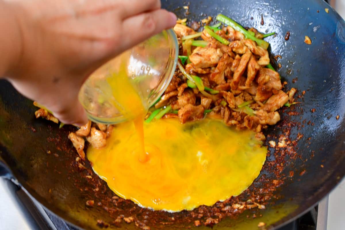 adding whisked egg to the wok