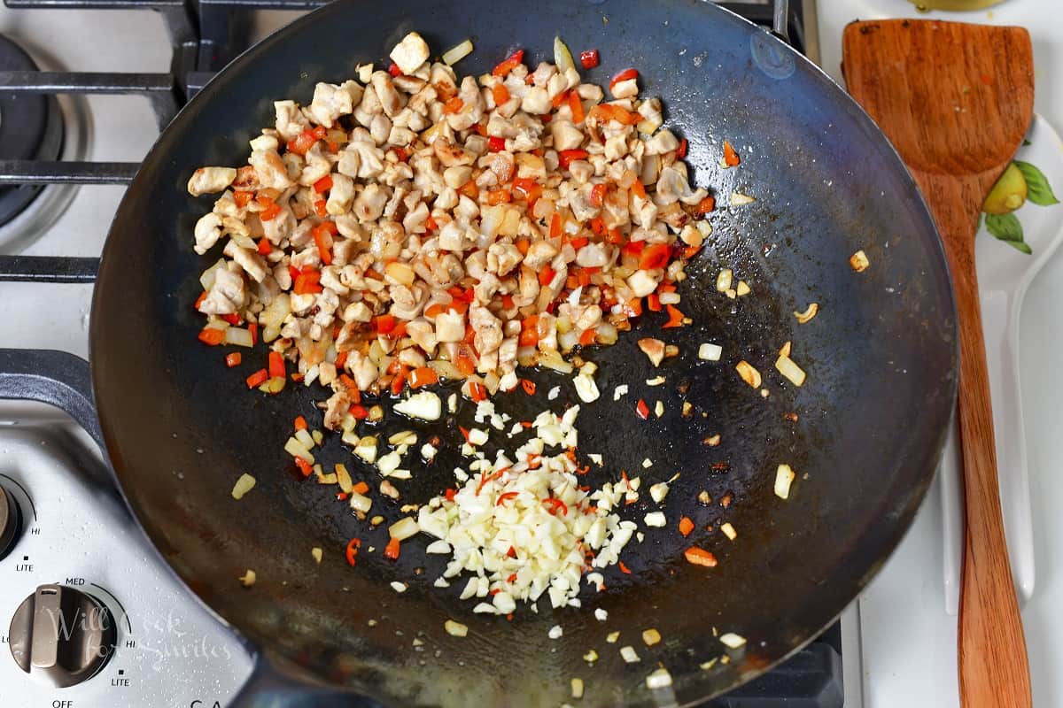 adding minced garlic and Thai pepper to the wok
