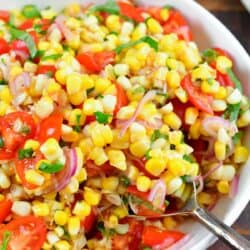 scooping out some tomato corn salad from the bowl