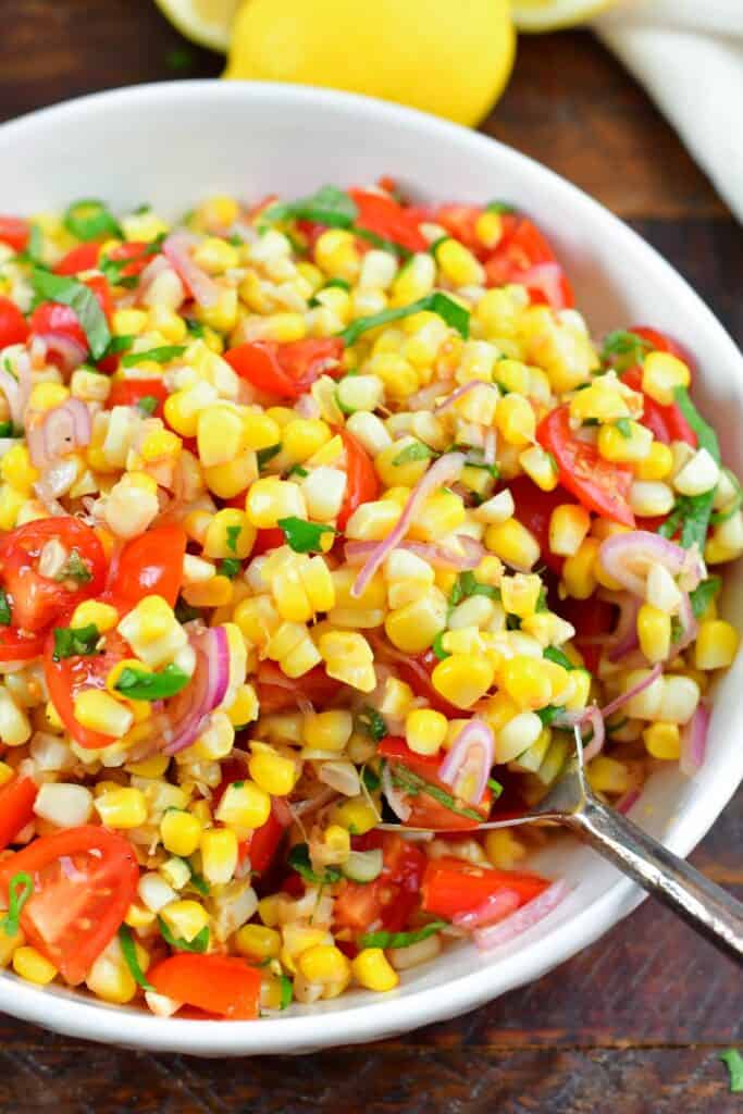 scooping out some tomato corn salad from the bowl