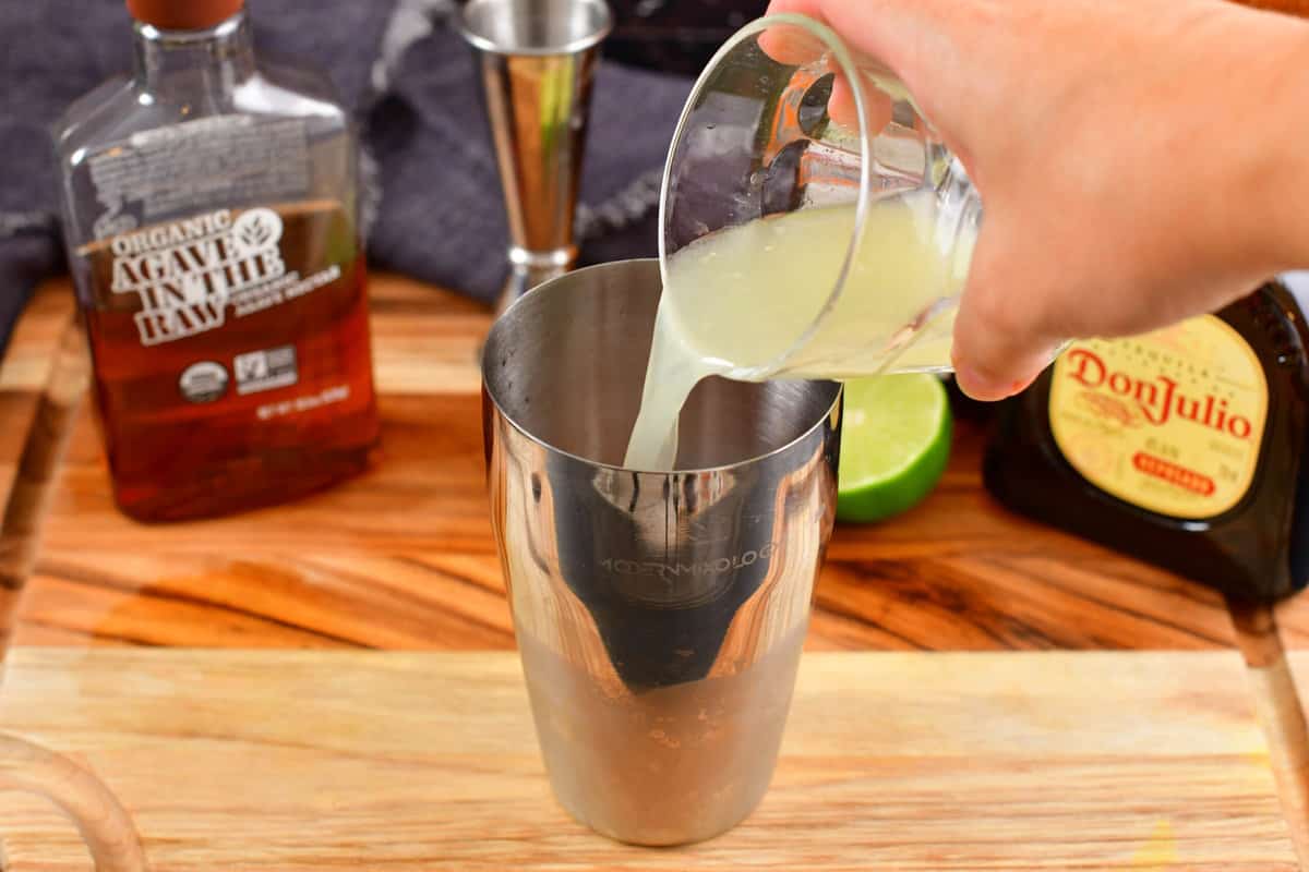 pouring in lime juice into the cocktail shaker