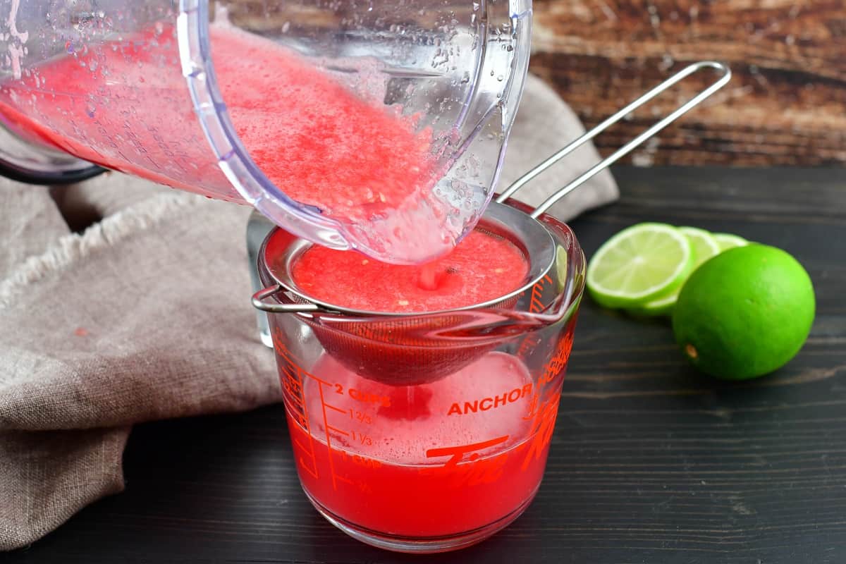 straining watermelon juice into measuring glass