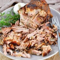 pulled pork on the plate with forks, garlic bulb and rosemary.