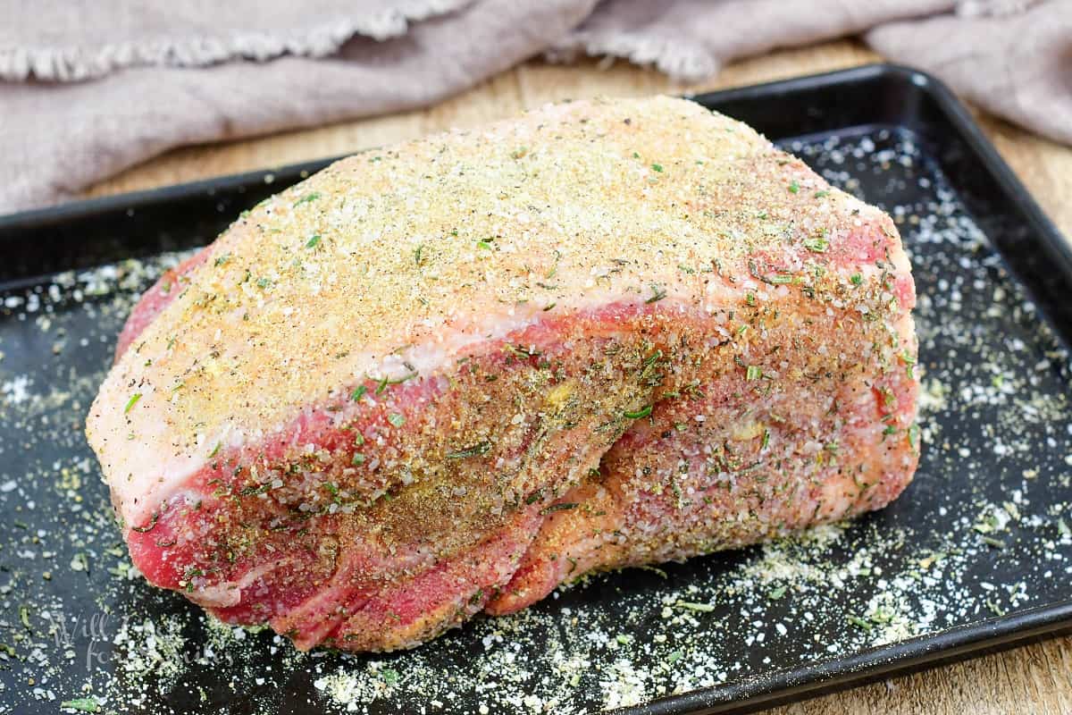 seasoned pork shoulder on the black metal baking sheet.