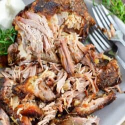 top view of pulled pork in the plate with forks and rosemary.