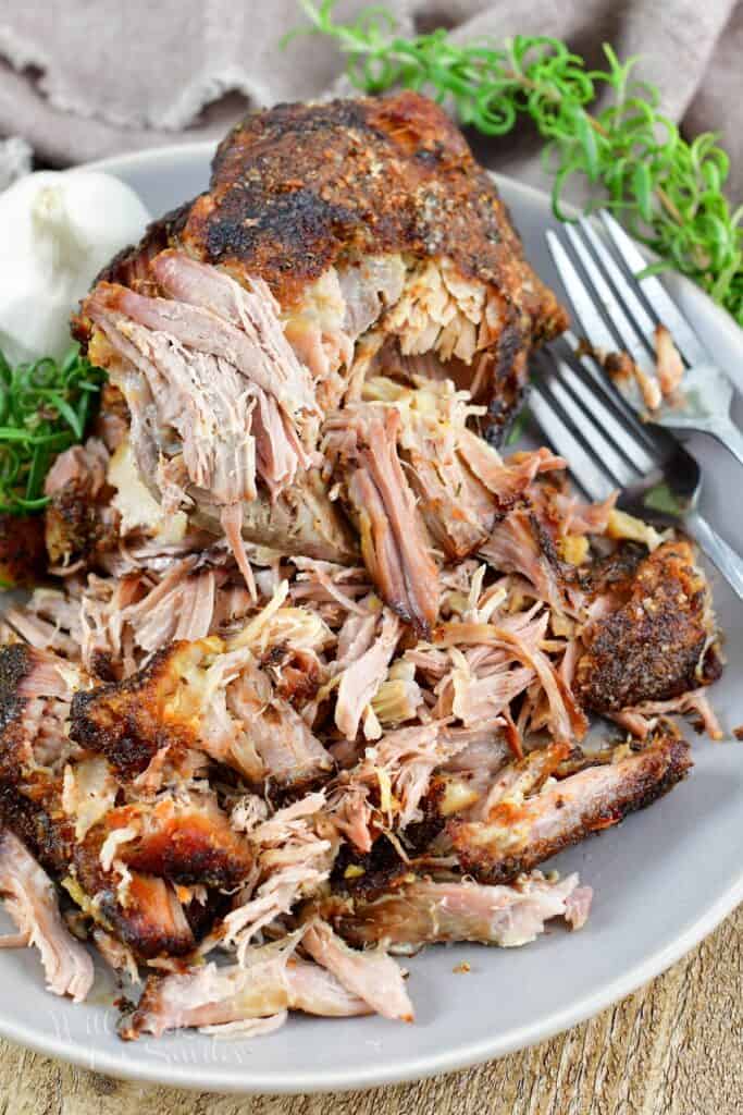 top view of pulled pork in the plate with forks and rosemary.