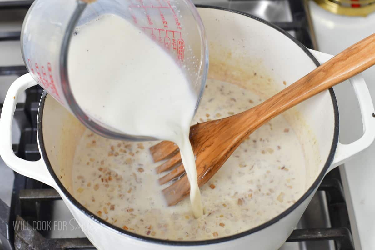 adding milk to the pot with veggies and flour.
