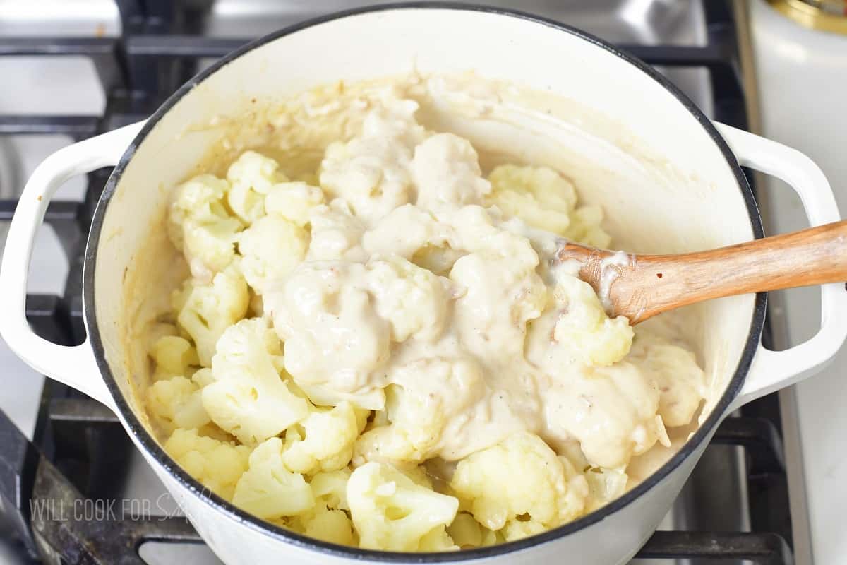 stirring blanched cauliflower with the cheese sauce.