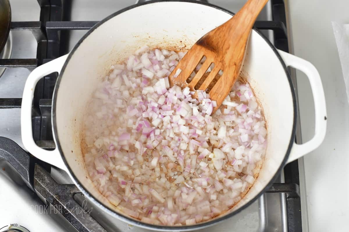 diced shallots cooking in a white pot.