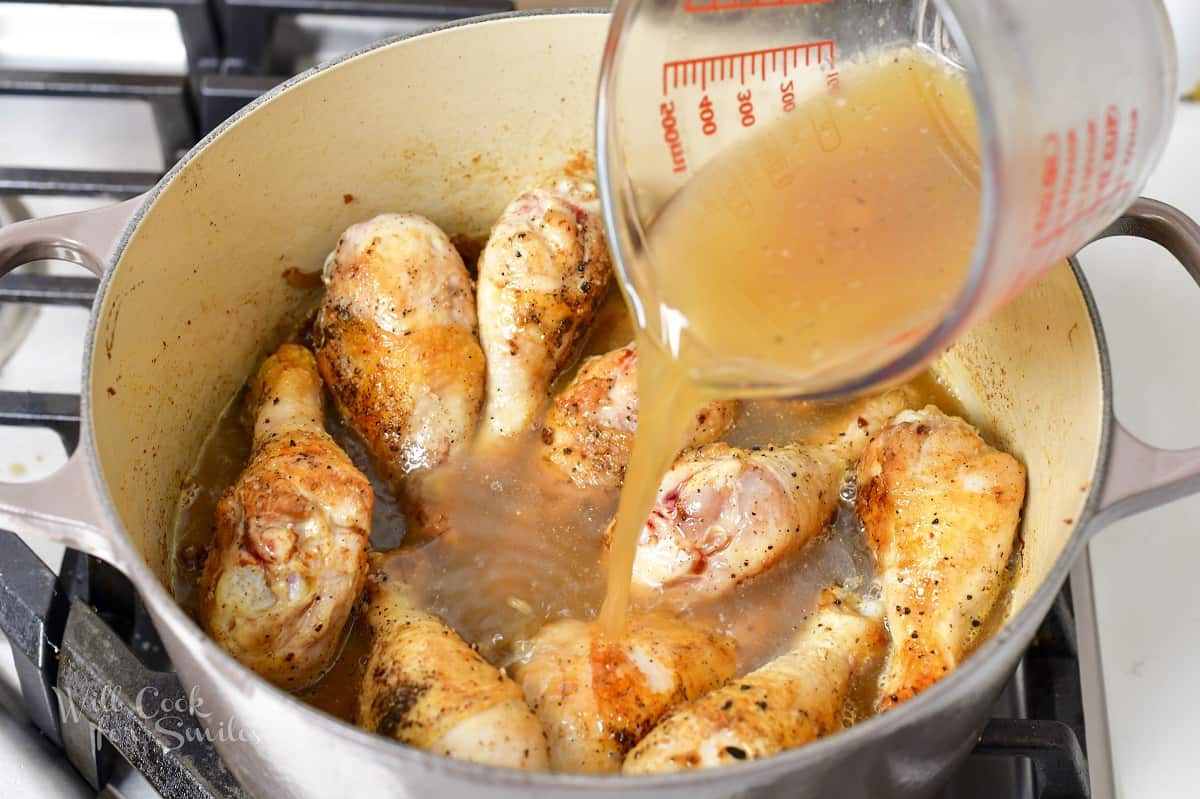 pouring in broth mixture into the pot with chicken