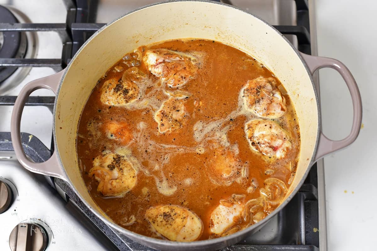chicken covered in broth in a Dutch oven