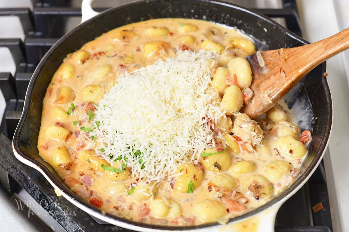 adding grated parmesan cheese to the creamy gnocchi