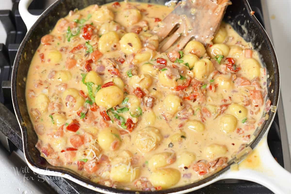 creamy gnocchi and veggies in sauce in a pan