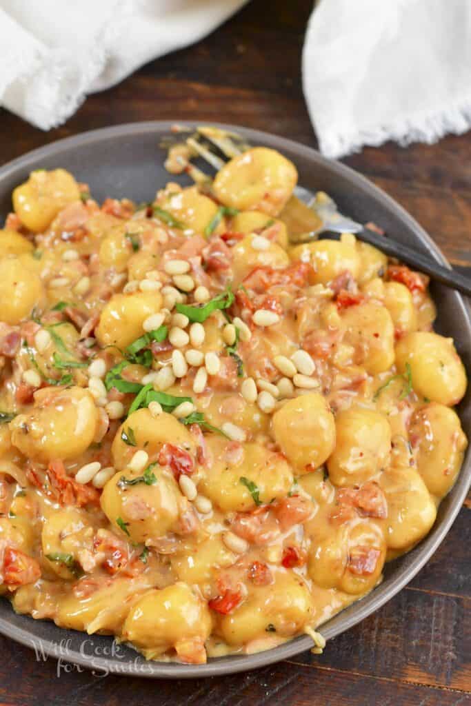 top view of creamy gnocchi dish with pine nuts and basil