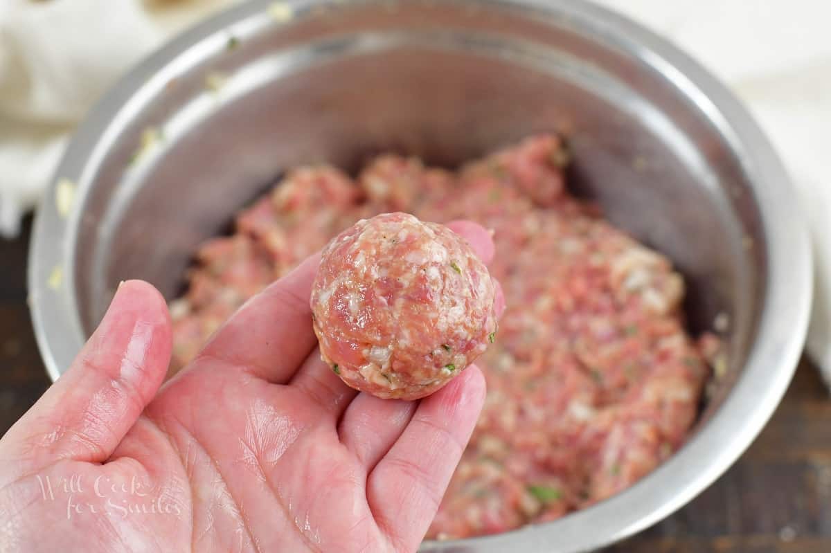holding a rolled meatball next to the mixing bowl