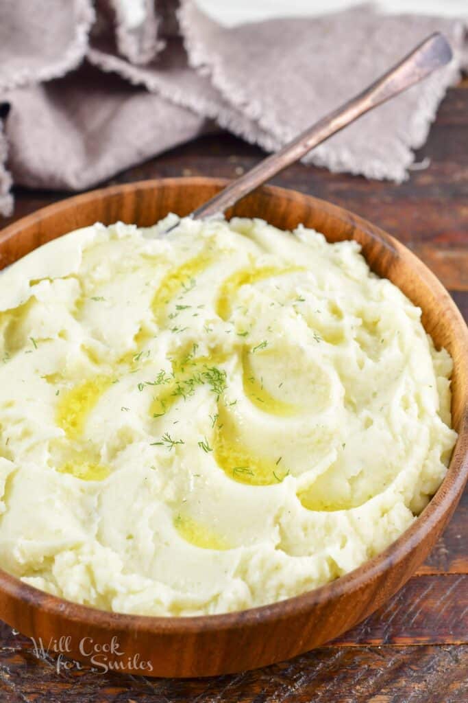 mashed potatoes with butter and a spoon in a wooden bowl.